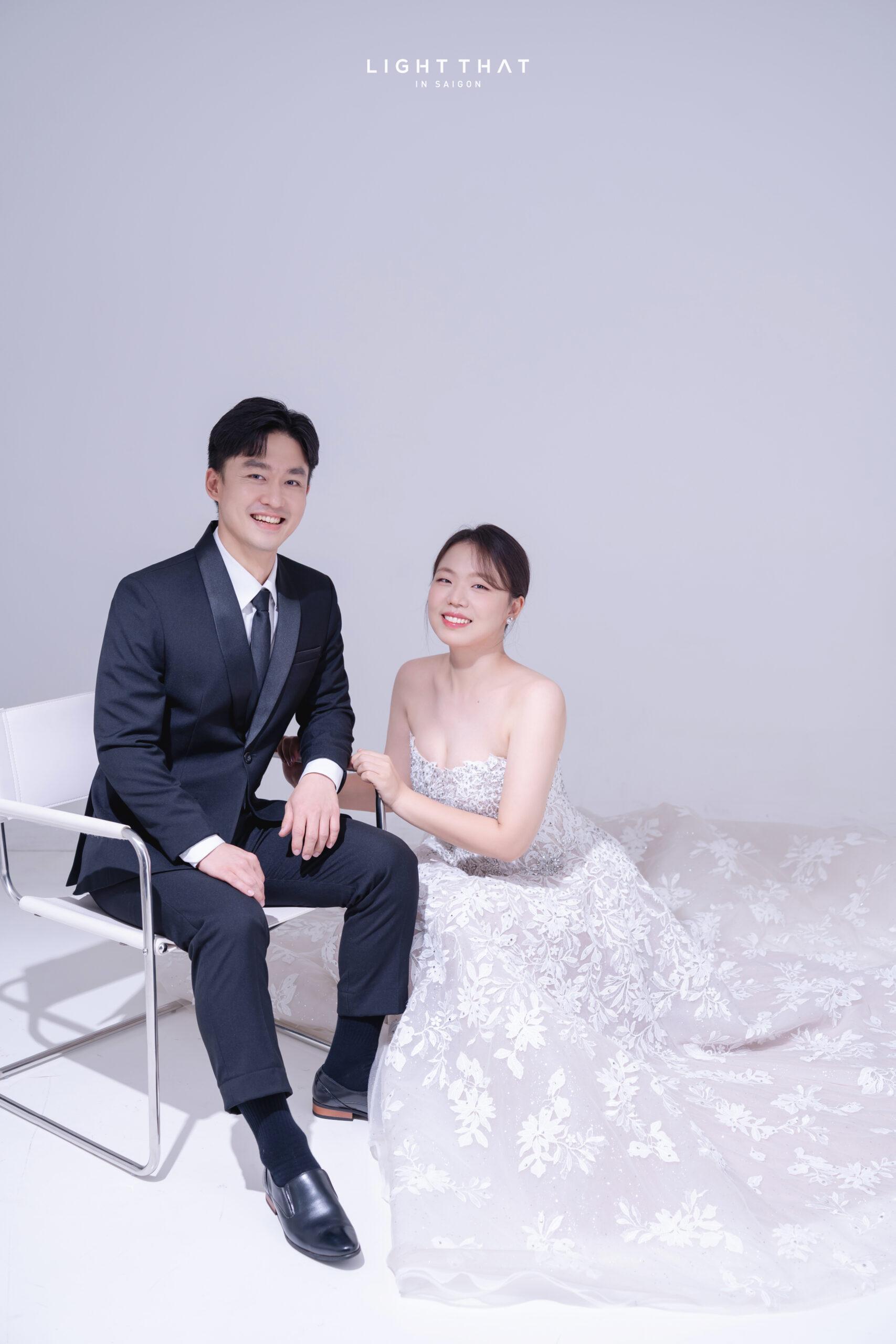 Tư thế ngồi nhẹ nhàng giúp cặp đôi tạo dáng chụp ảnh cưới phông trơn đẹp tự nhiên