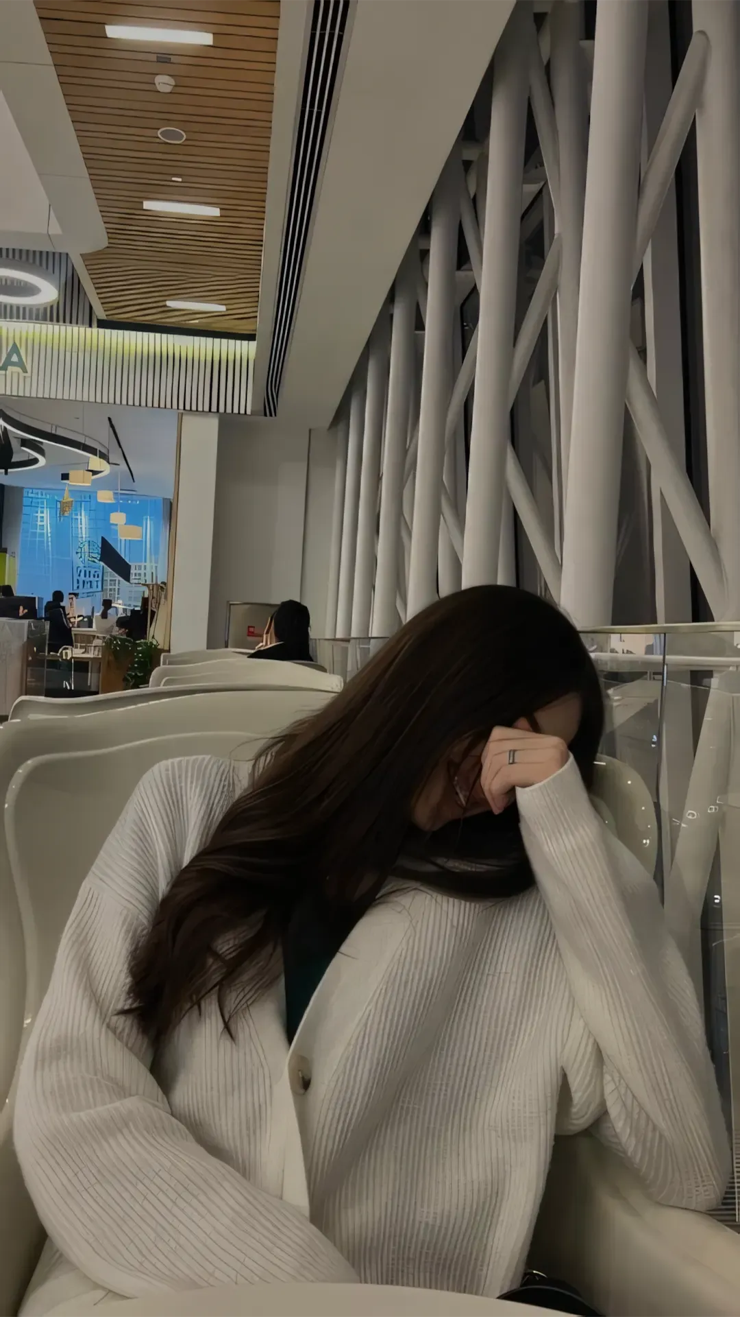 Cô gái ngồi gục đầu trong không gian tối, ánh sáng yếu nhấn mạnh sự cô đơn và mệt mỏi tinh thần