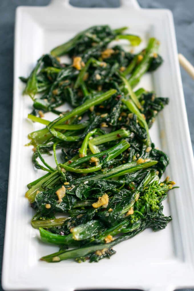 A plate of stir-fried choy sum pieces with visible bits of garlic and ginger.
